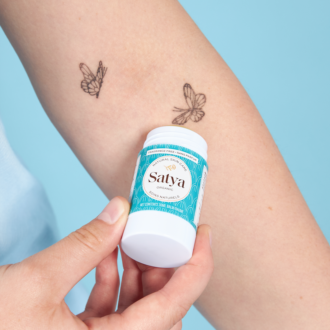 A person applying the Satya Multi Use Easy Glide Stick to their arm as tattoo aftercare.