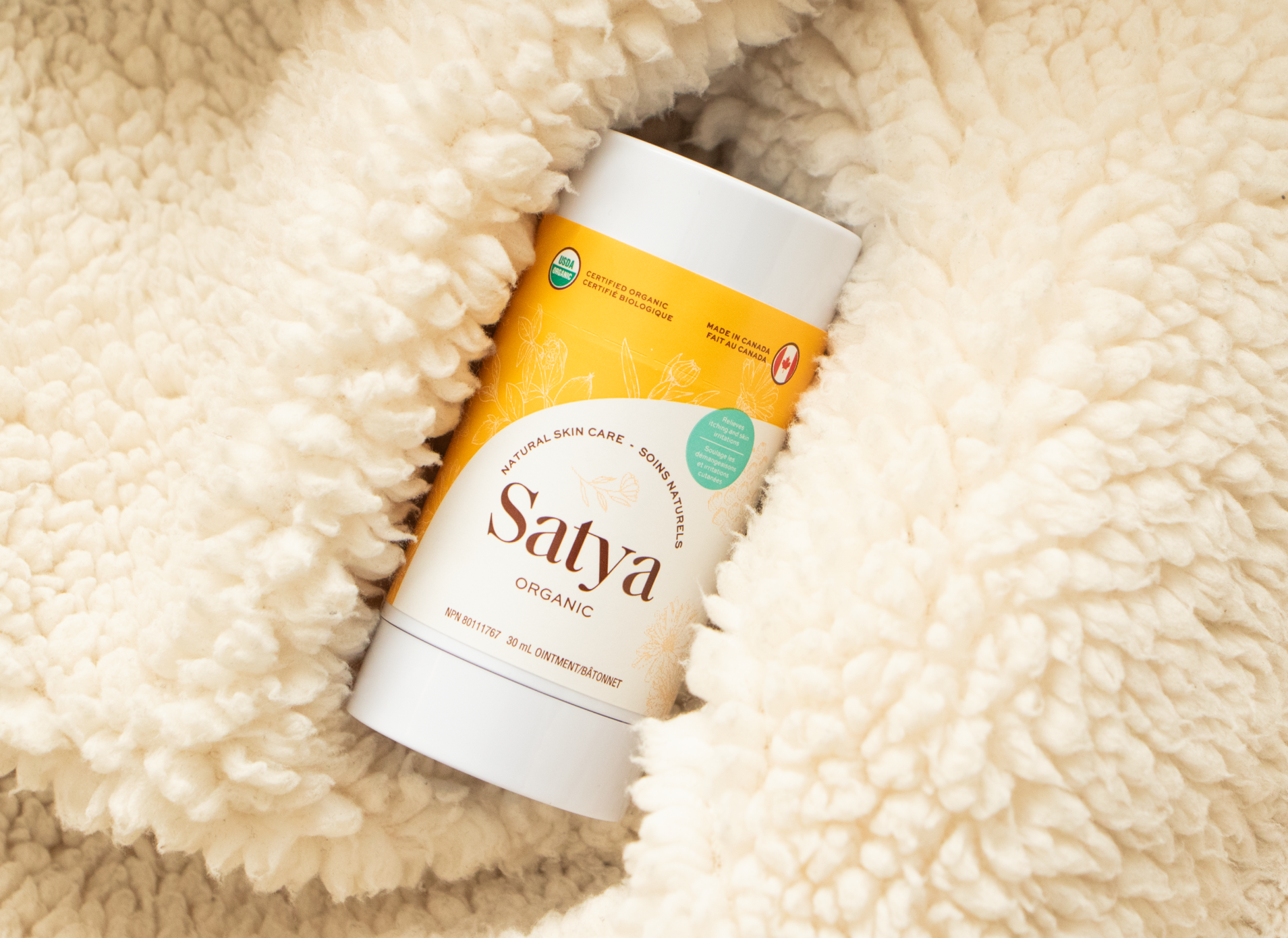 Satya Eczema Relief Stick snuggled into a blanket.