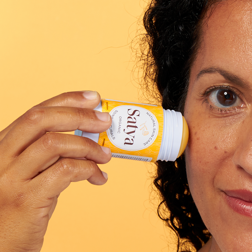 A person applying Satya Eczema Relief Glide Stick to their face.