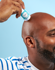 A person applying the Satya Multi Use Easy Glide Stick to their scalp.