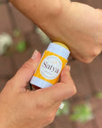 A person applying Satya's Eczema Easy Glide Stick to their hand.